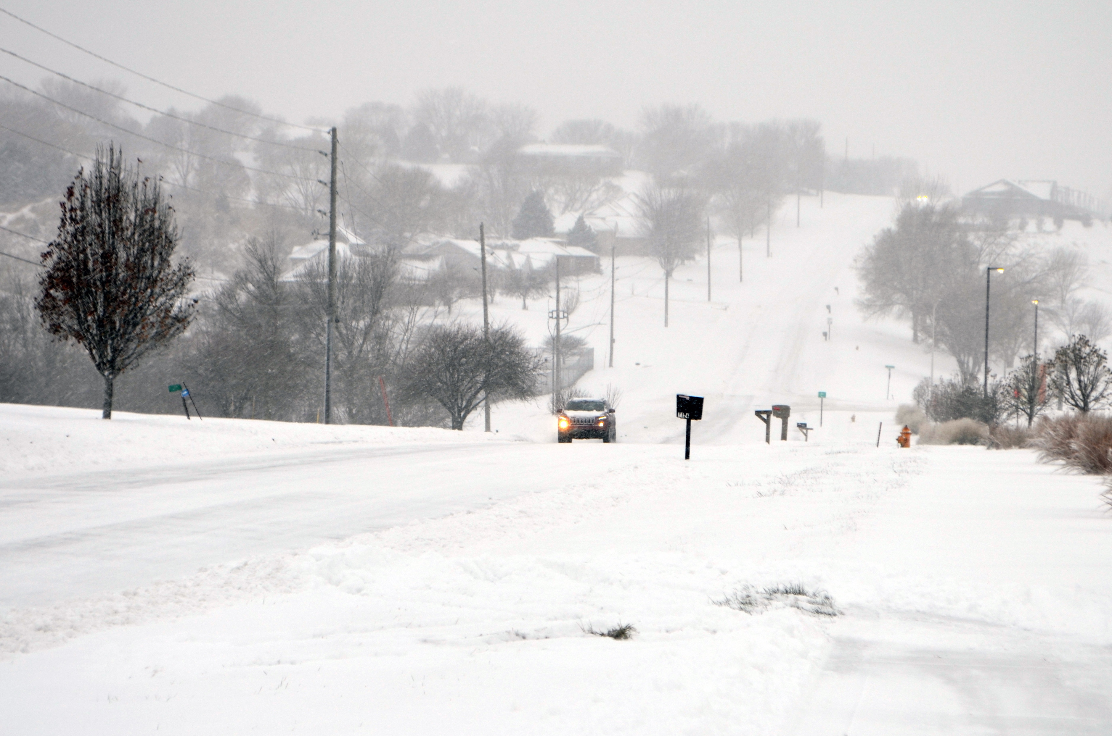 A car drives up a snowy road in Sioux City, Iowa, on Saturday.